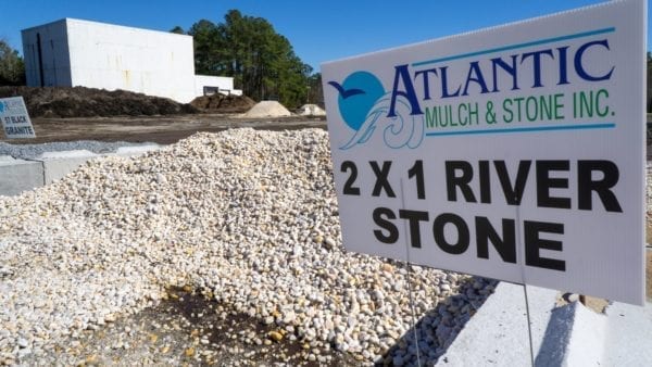 mound of 2x1 white River Stone with Atlantic Mulch & Stone sign to the right