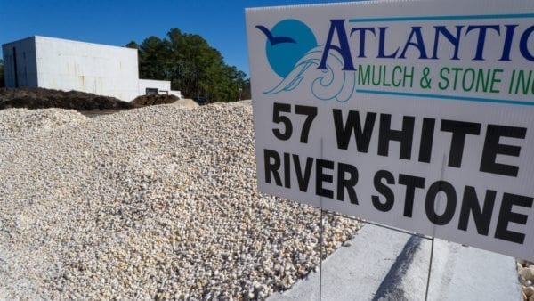 mound of 57 white river stone with Atlantic Mulch & Stone sign to the right