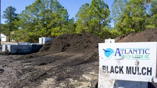 mound of black mulch with Atlantic Mulch & Stone sign on the right